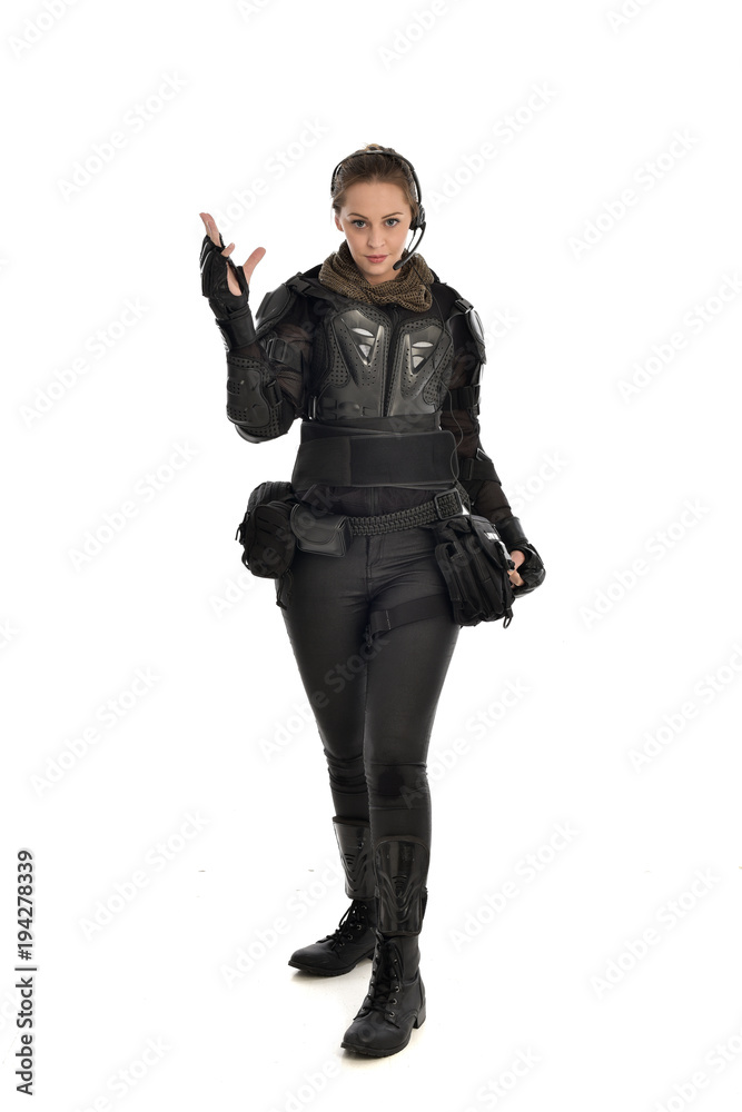 full length portrait of female  soldier wearing black  tactical armour with arms raised, isolated on white studio background.