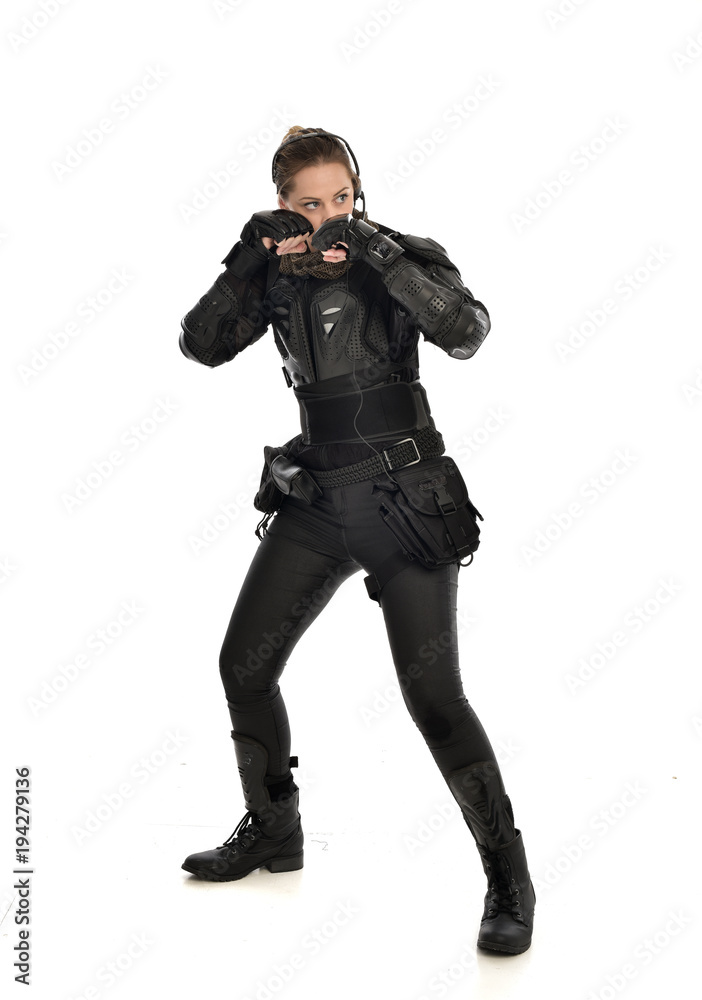 full length portrait of female soldier wearing black tactical armour with arms raised, isolated on white studio background. full length portrait of female soldier wearing black tactical armour with arms raised, isolated on white studio background.
