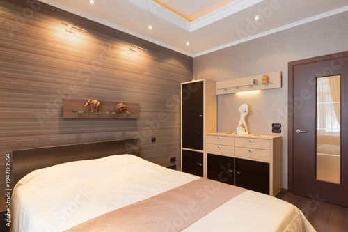 bedroom in brown tones with designer details on wall and  door