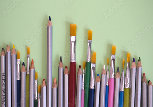 Multicolored brushes and pencils on a yellow background