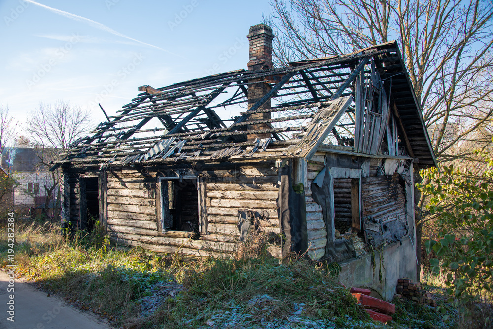 Burned wooden house among green trees and shrubs Burned wooden house among green trees and shrubs