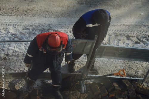 Working men in the form of standing around a sand pit 