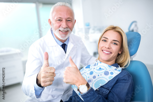 Smiling and satisfied experienced dentist and young patient after successful treatment