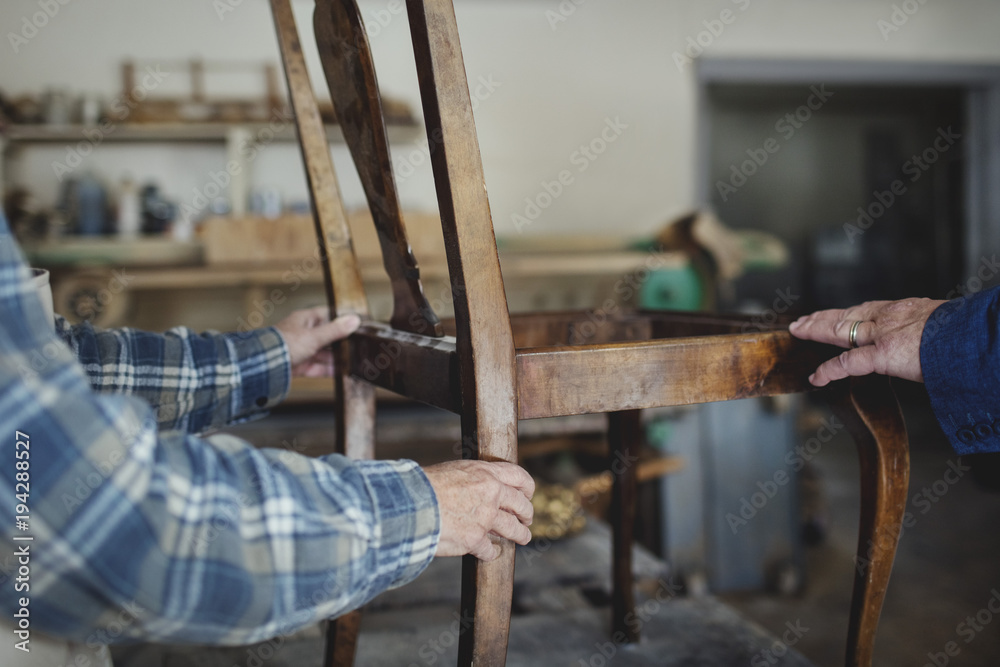 Close up of carpenter holding chair Close up of carpenter holding chair