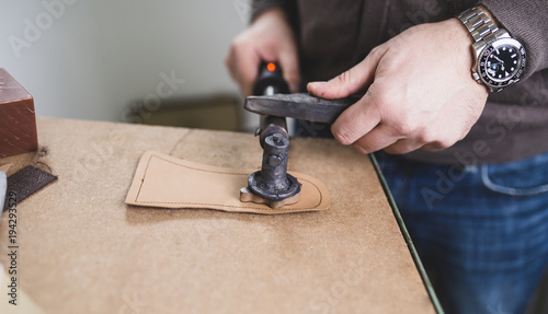 Close up of a male shoemaker working with leather textile at his workshop. 