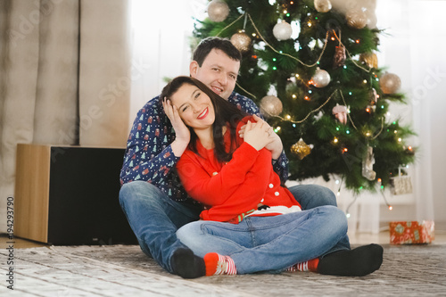 Beautiful couple in festive closes stands poses before a Christmas tree © andriychuk