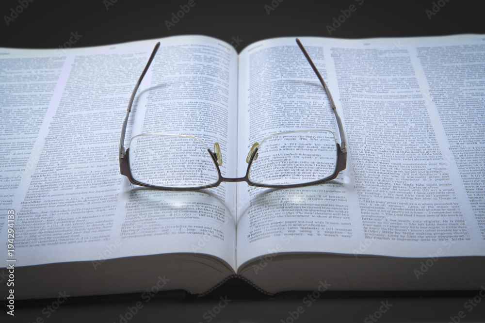 Obraz premium Eyeglasses on an opened text book
