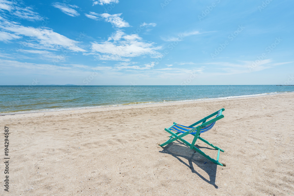 Beach chairs on the white sand with cloudy blue sky and sun