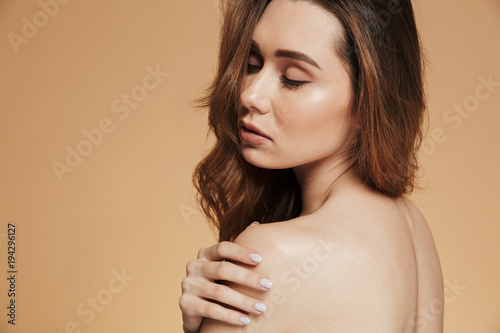 Young woman with closed eyes standing isolated over beige