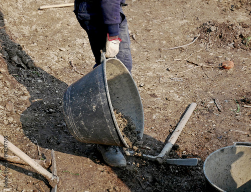 Man at work with shovel, pick and bucket on a rough ground to cultivate.  photo