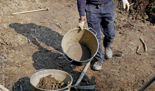 Man at work with shovel, pick and bucket on a rough ground to cultivate.  photo