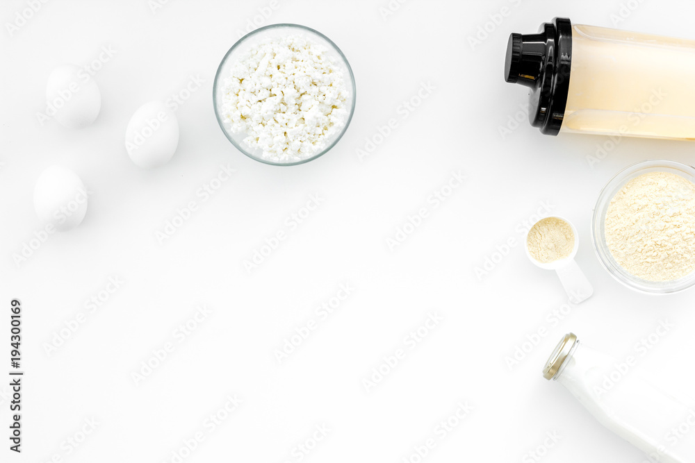 Protein diet for the athlete Scoop of protein near shaker, milk, eggs, cottage cheese on white background top view copy space