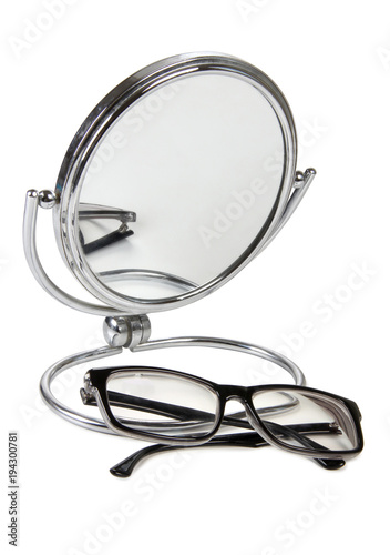 Mirror in a metal frame and glasses on a white background