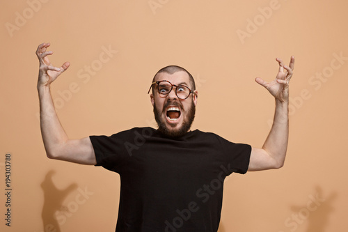 The young emotional angry man on pastel studio background photo