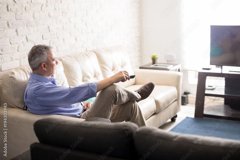 Mature man relaxing at home watching tv Mature man relaxing at home watching tv