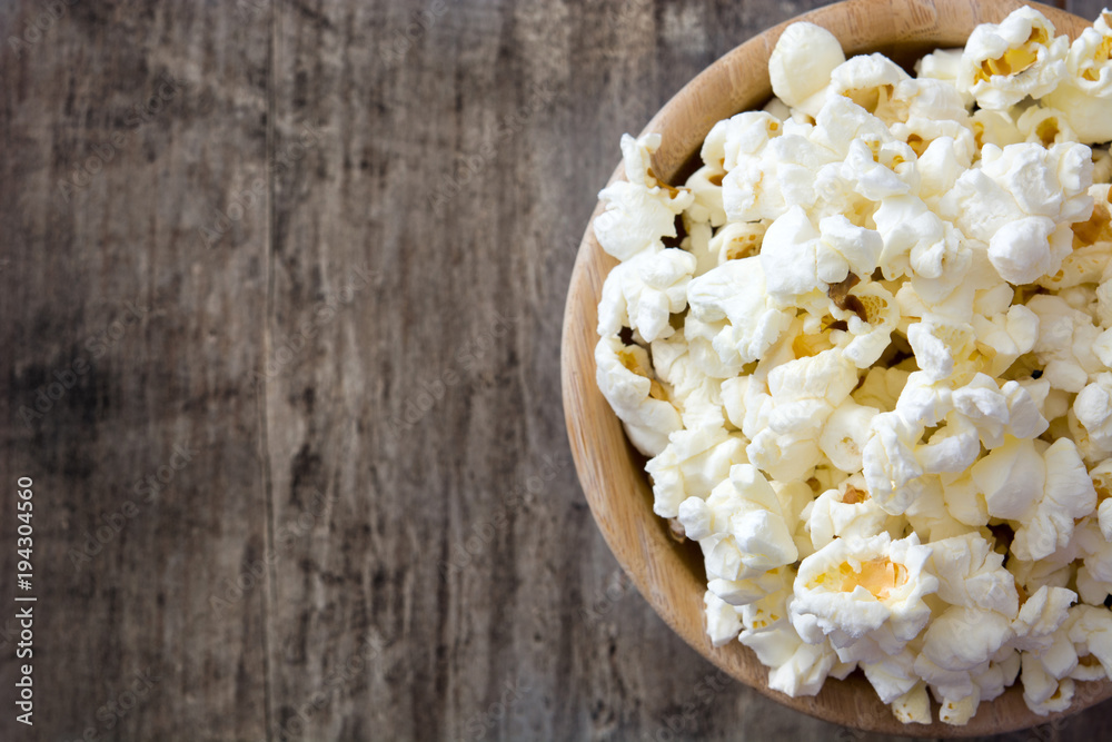 Popcorn in bowl on wooden table. Top view

