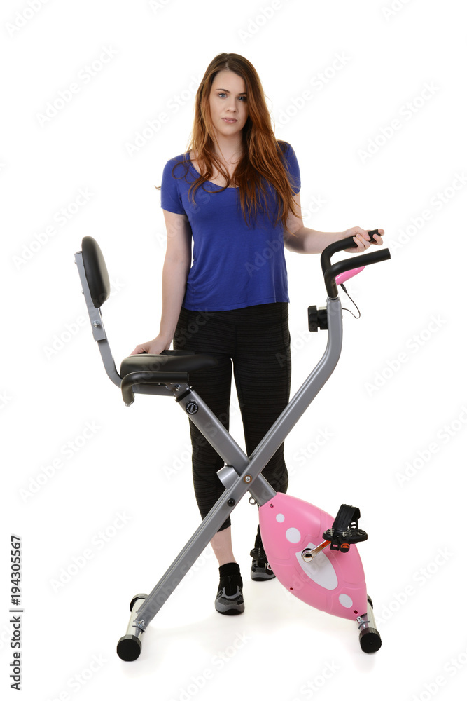 young woman standing by exercise bike young woman standing by exercise bike