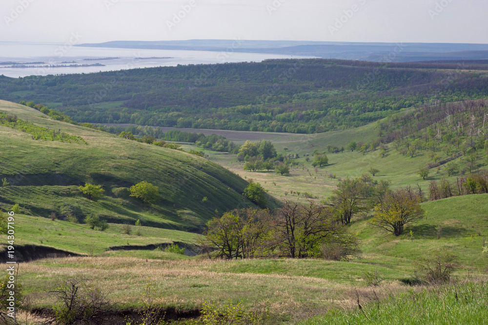 View from the mountain to the green hills and the lowlands of the river. Bright spring greens.