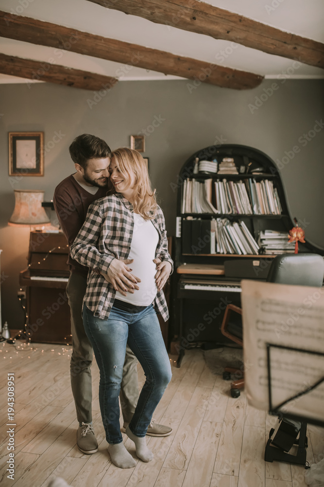 Pregnant woman and happy man in the house