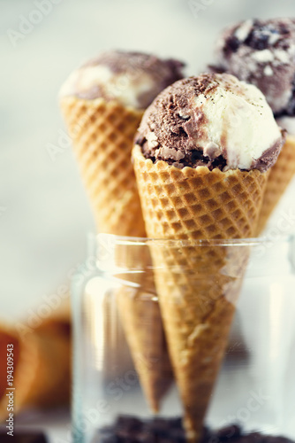 Chocolate and coffee ice cream in waffle cone with coffee beans on grey stone background. Summer food concept, copy space. Healthy gluten free ice-cream. Banner