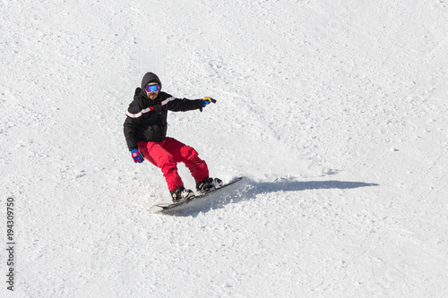 Uomo sullo snowboard che scende da una parete innevata