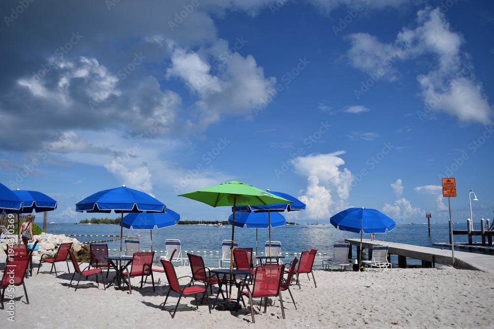 Seaside beach with tables and umbrellas on sunny day with blue sky