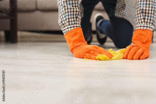 Unrecognizable man cleaning floor with rag