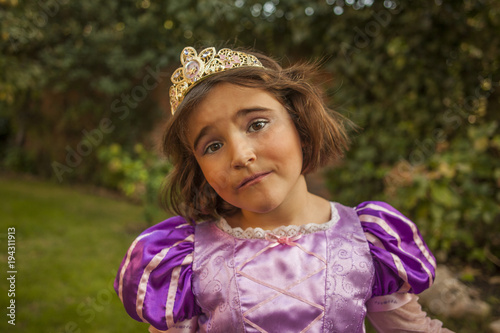 Close up portrait child in a purple princess costume, make up and crown. Outdoors.