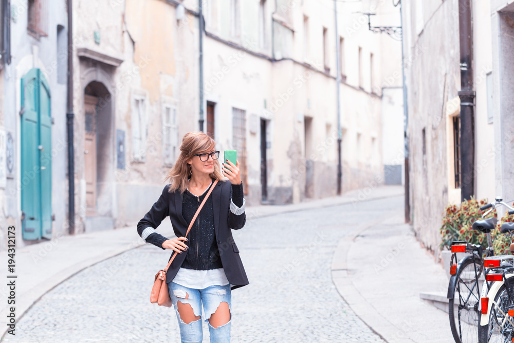 Cute woman holding cellphone in urban surroundings. Cute woman holding cellphone in urban surroundings.