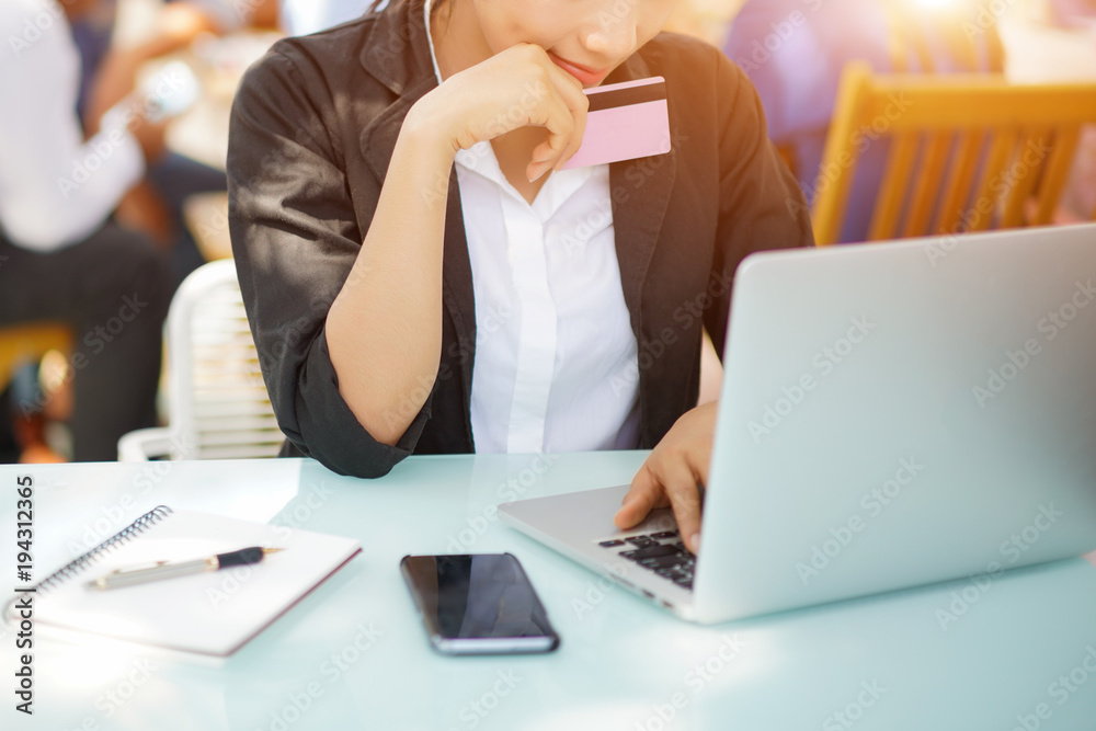 Young woman holding credit card and using laptop computer. Online shopping concept Young woman holding credit card and using laptop computer. Online shopping concept