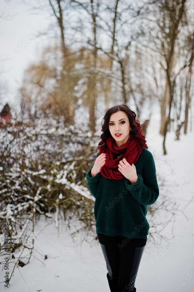 Brunette girl in green sweater and red scarf outdoor on evening winter day. Brunette girl in green sweater and red scarf outdoor on evening winter day.