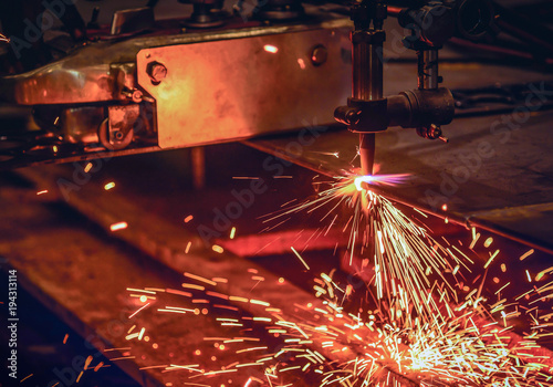 Worker cutting steel plate with acetylene welding cutting torch and bright sparks in factory