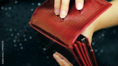 Close-up of a girl closes her red leather wallet and holds it in her hands in slow motion.