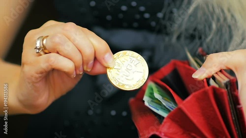 SLOW MOTION: close-up of a girl holds a wallet in her hand and places a gold Bitcoin in a wallet.
