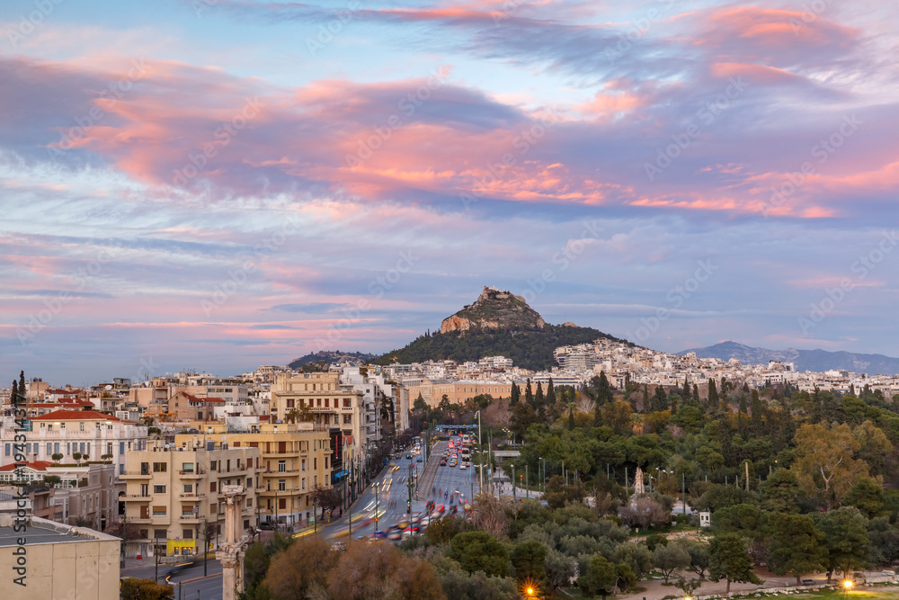 Mount Lycabettus towering above of the roofs of Old Town at gorgeous sunset in Athens, Greece