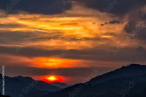 Beautiful landscape of a big setting sun over the silhouette of the mountains, Salciua, Romania © mihaelastancu