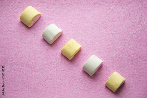Top view of pastel colored marshmallow on beautiful pink background. Wallpaper texture.