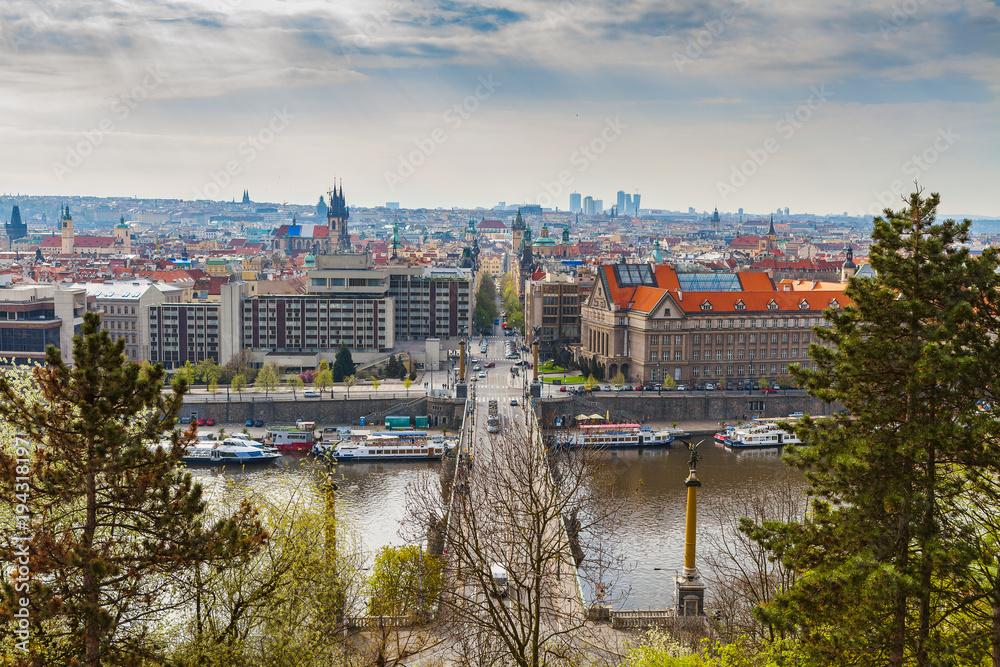 Naklejka premium Scenic aerial view of the Old Town architecture and bridge over Vltava river in Prague, Czech Republic. Trees of the park at the foreground.
