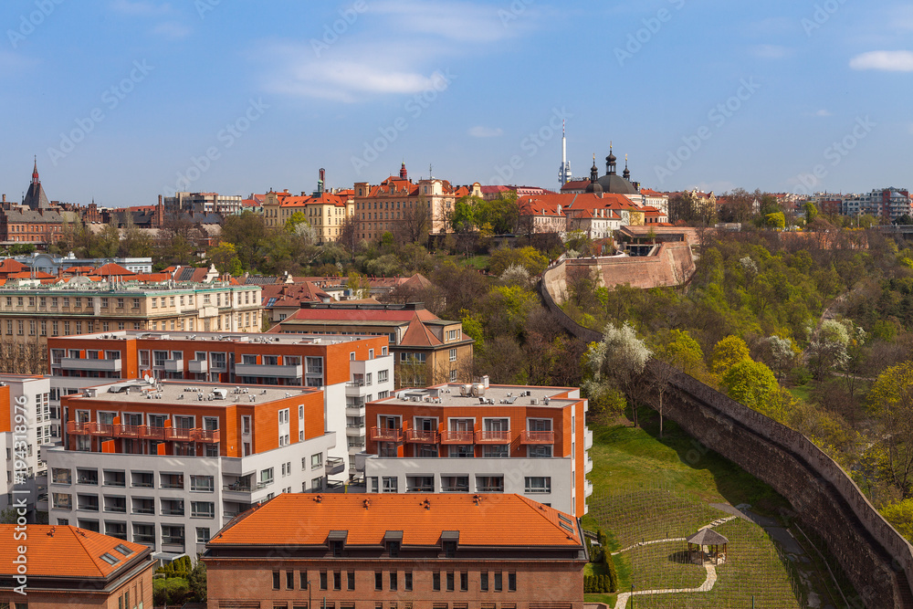 Obraz premium Prague skyline with wall, castle and living blocks red rooftops with park and trees