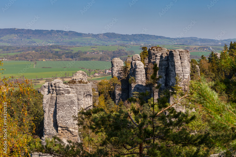 Sandstone steep rocks look like fingers in the forest. Sunny summer day. Hruba skala or Bohemian Paradise park. Sandstone steep rocks look like fingers in the forest. Sunny summer day. Hruba skala or Bohemian Paradise park.