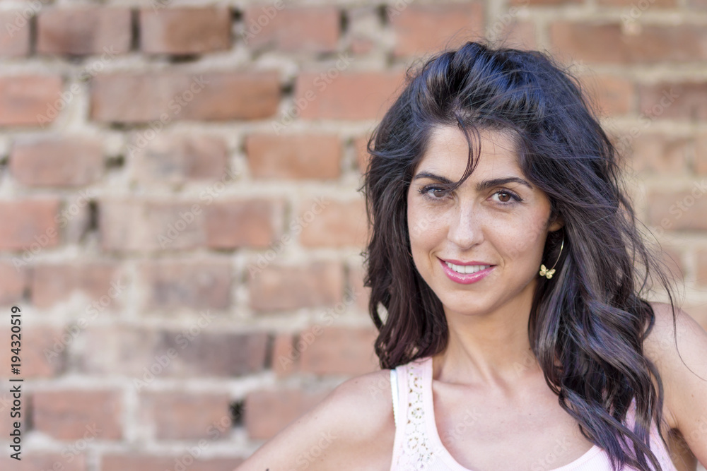 Portrait of Beautiful Happy Young Woman with Curly Hair on a Brick Background Portrait of Beautiful Happy Young Woman with Curly Hair on a Brick Background