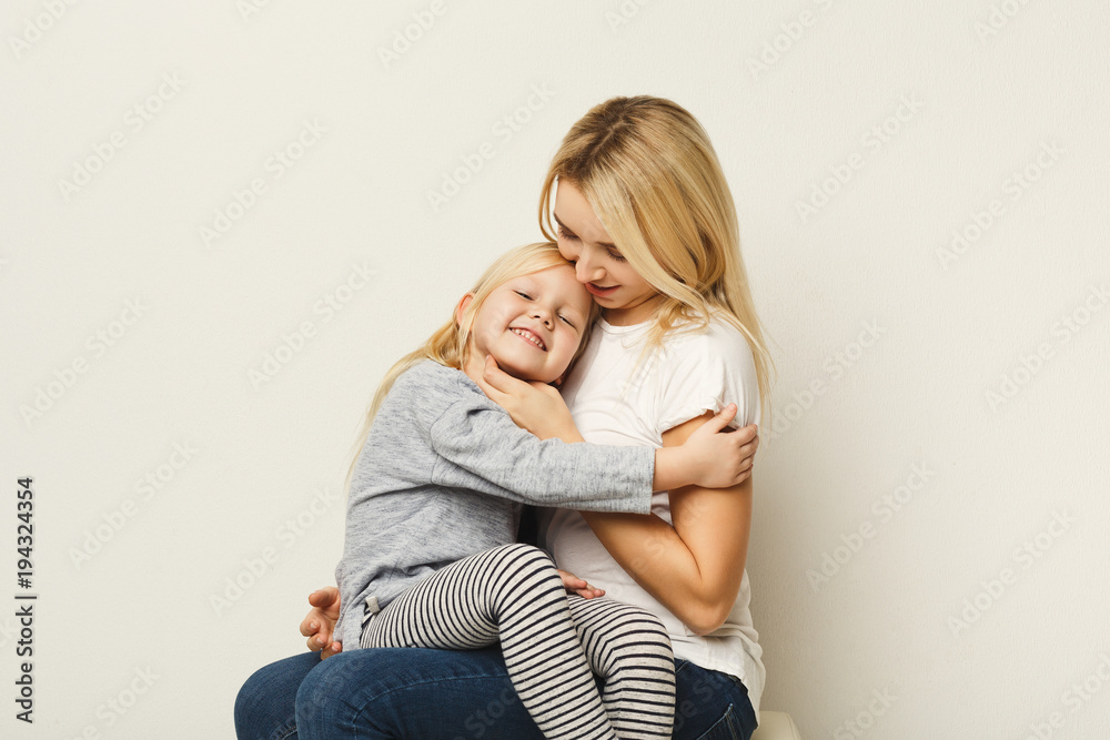 Happy mother and daughter embracing at white studio background Happy mother and daughter embracing at white studio background