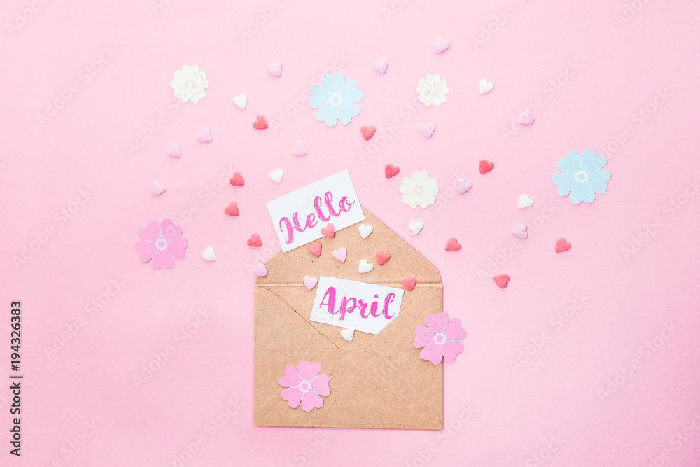 Multicolor sweets sugar candy hearts, handcraft paper flowers and cards with Hello April lettering fly out of craft paper envelope on pink background . Spring concept. Space for text. Horizontal. Multicolor sweets sugar candy hearts, handcraft paper flowers and cards with Hello April lettering fly out of craft paper envelope on pink background . Spring concept. Space for text. Horizontal.