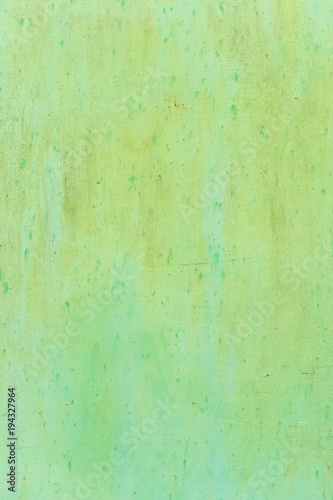 Textured metal surface carelessly colored green paint and faded in the sun in pale gray with rusty specks.