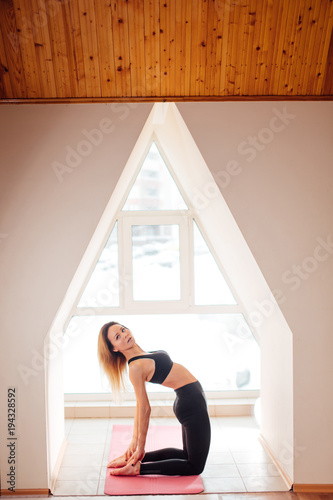 young attractive woman in back reversed yoga pose, side view, dressed in black