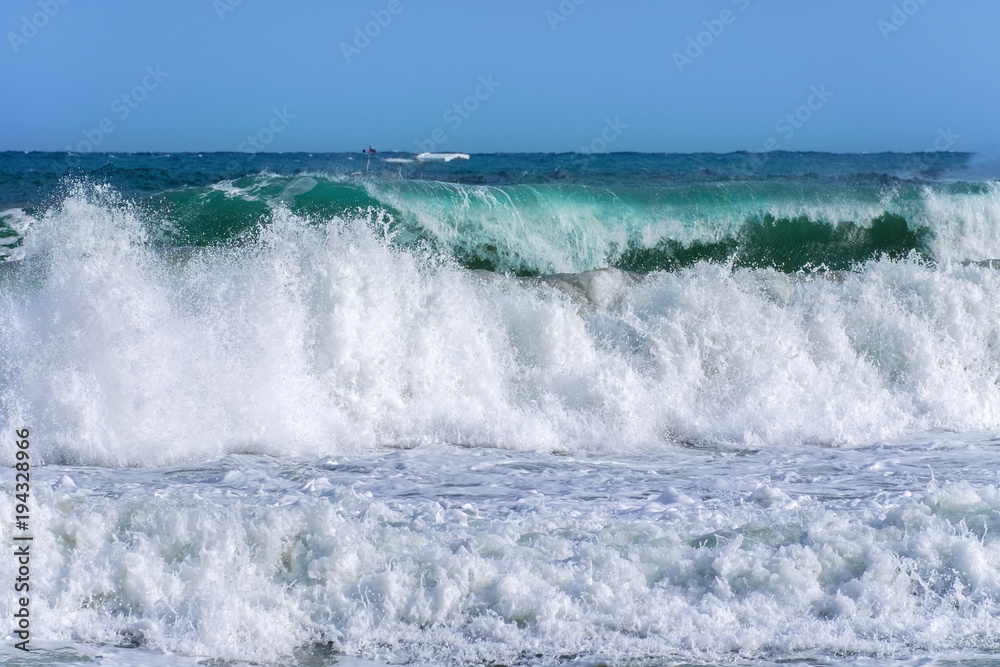 Beautiful big waves of the sea in the summer bright blue, turquoise colors in the early morning in sun light on a pure blue sky.