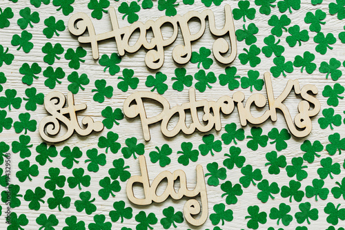 Happy St Patrick's Day wooden lettering with handmade paper shamrocks over a rustic wooden background