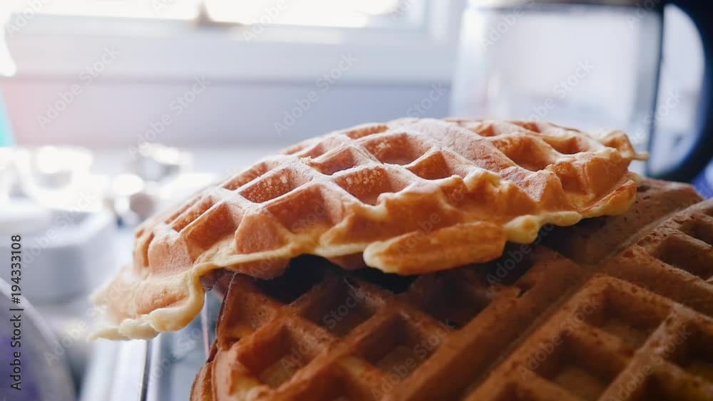 Medium shot of a Belgian waffle falling on a pile of waffles in slow