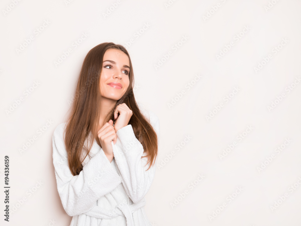 beautiful young woman with long hair wearing bath robe and posing on grey background with copy space beautiful young woman with long hair wearing bath robe and posing on grey background with copy space