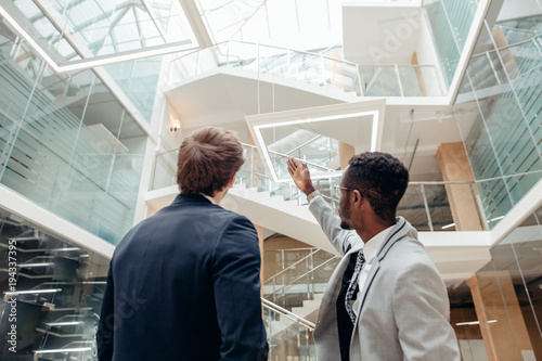 shot of afroamerican estate agent with potential client inside an empty office space photo